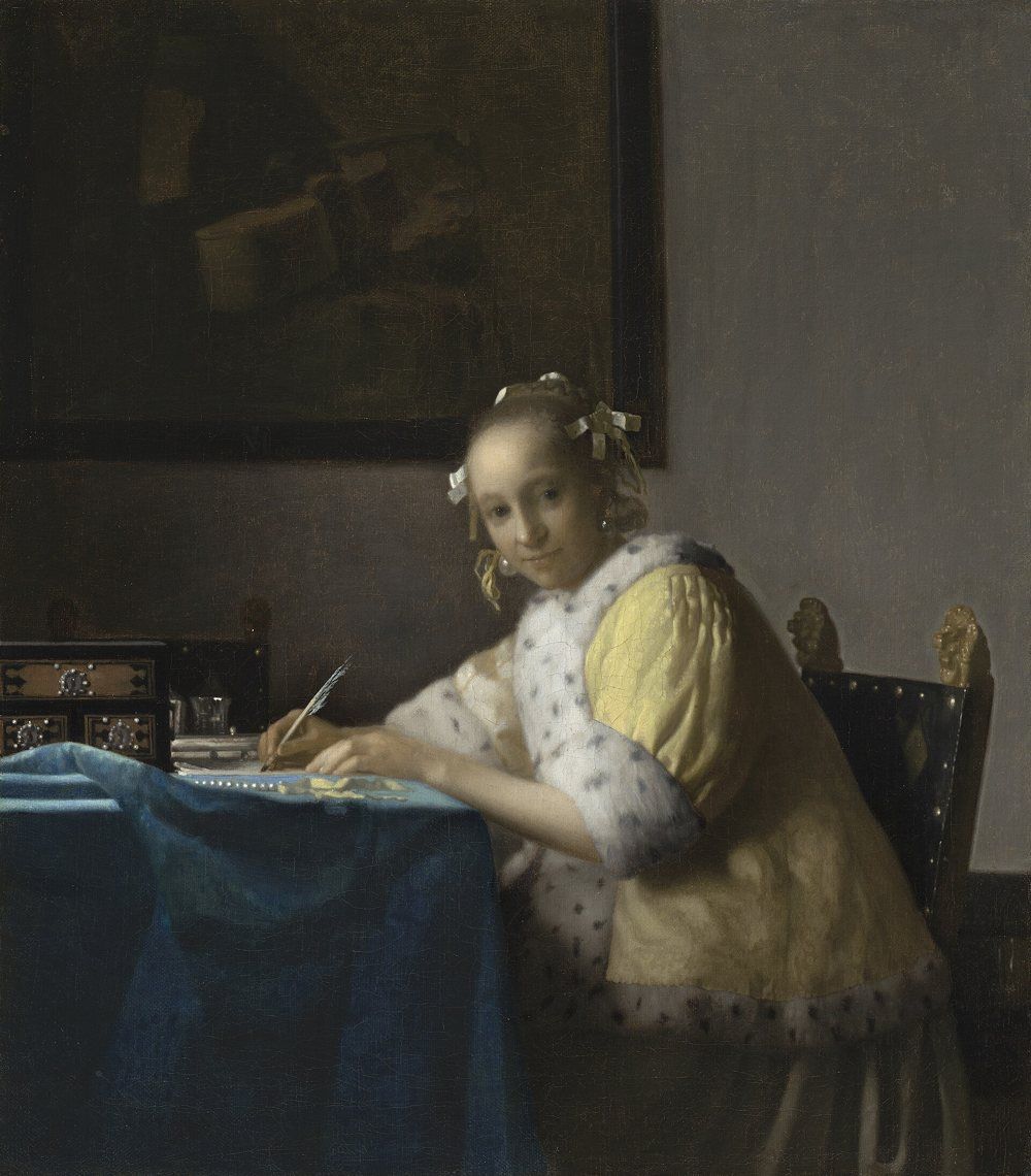 Painting by Vermeer: a woman writes at her desk and looks at the viewer